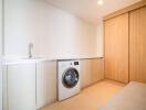 Compact laundry room with modern washing machine and built-in cabinetry