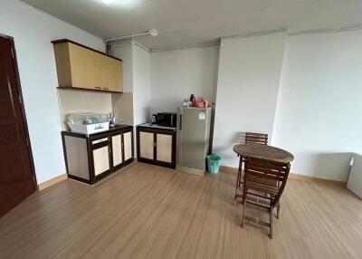 Compact kitchen with wooden cabinets, laminate flooring, and a small dining area