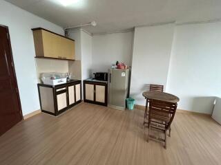 Compact kitchen with wooden cabinets, laminate flooring, and a small dining area