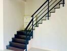 Modern staircase in a residential home with white walls and dark steps