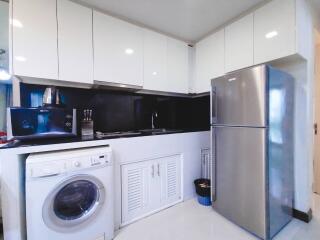 Modern kitchen with white cabinets, stainless steel appliances, and washing machine