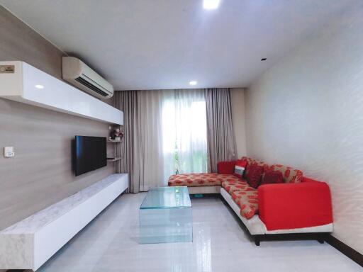 Modern living room interior with comfortable red sofa, sleek TV console and large window with curtains