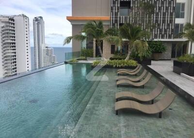 Modern infinity pool with lounge chairs and city skyline view at a luxury apartment complex