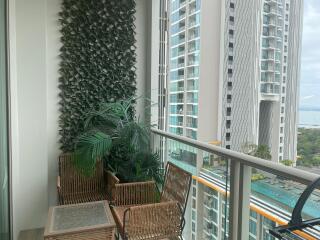 High-rise apartment balcony with ocean view, plant wall, and wicker furniture