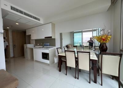 Modern apartment interior with an open plan living, dining, and kitchen area, featuring large windows with a city view