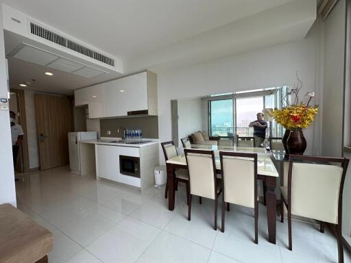 Modern apartment interior with an open plan living, dining, and kitchen area, featuring large windows with a city view