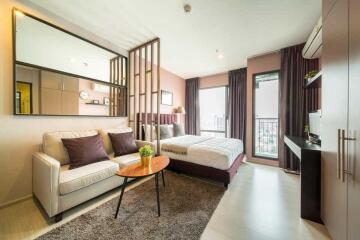 Modern studio apartment interior with combined living and sleeping area, kitchenette and balcony