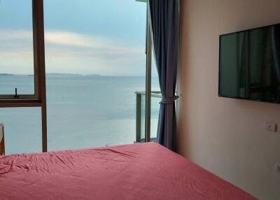 Bedroom with a view of the sea, large window, and wall-mounted television