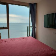 Bedroom with a view of the sea, large window, and wall-mounted television