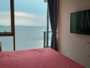 Bedroom with a view of the sea, large window, and wall-mounted television