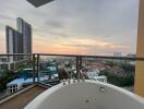 Spacious balcony with a bathtub overlooking a cityscape at sunset