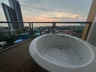 Jacuzzi on a high-rise balcony overlooking the city at sunset