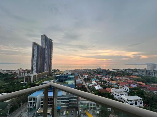 Scenic view from balcony at dusk with urban skyline and setting sun