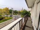 Spacious balcony with a view of a residential street and greenery