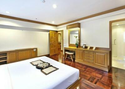 Spacious bedroom with wooden flooring and built-in cabinets