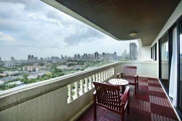 Spacious balcony with wooden flooring, outdoor furniture, and urban skyline view