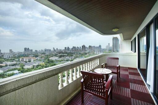 Spacious balcony with wooden flooring, outdoor furniture, and urban skyline view