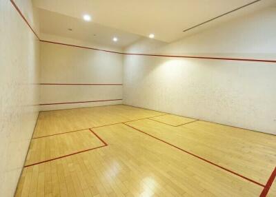 Indoor squash court with wooden flooring and bright lighting