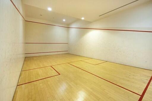 Indoor squash court with wooden flooring and bright lighting