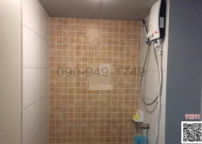 Bathroom with beige wall tiles and running water heater