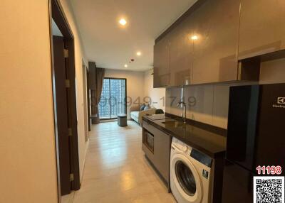 Interior view of an apartment showing the hallway leading to a living space with kitchen appliances on the right