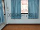 Empty room with tiled flooring, window with blue curtains, and air conditioning unit