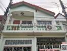 Two-story residential house with balcony and gated windows