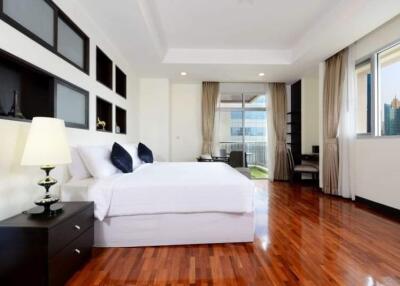 Spacious bedroom with hardwood floors, large bed, and balcony access