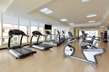 Modern gym facility with various exercise machines and large windows