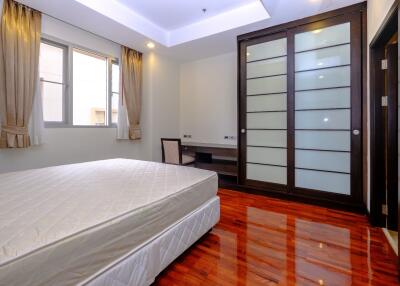 Spacious bedroom with polished hardwood floor and ample natural light