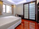 Spacious bedroom with polished hardwood floor and ample natural light