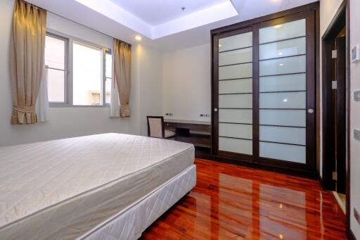 Spacious bedroom with polished hardwood floor and ample natural light