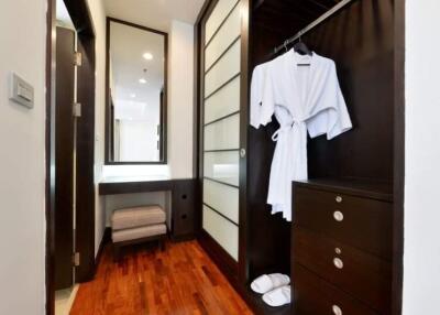 Modern bedroom with walk-in closet, wooden flooring, and mirrored wardrobe