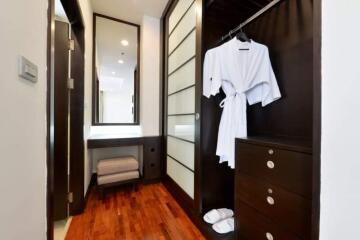 Modern bedroom with walk-in closet, wooden flooring, and mirrored wardrobe