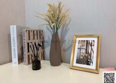 Decorative shelf with books, vase with dried flowers, and framed photo