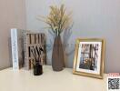 Decorative shelf with books, vase with dried flowers, and framed photo