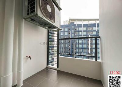 Spacious balcony with outdoor air-conditioning unit and view of exterior buildings