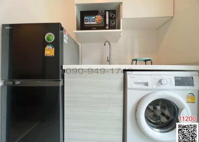 Modern kitchen area with appliances including a refrigerator and a washing machine