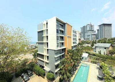 Modern apartment building with adjacent pool and green surroundings