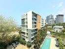 Modern apartment building with adjacent pool and green surroundings