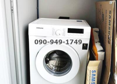 Compact laundry area with a new Samsung washing machine and storage space