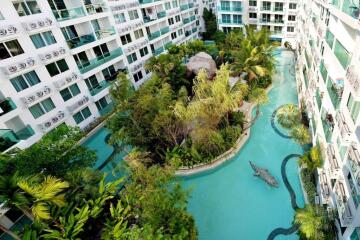 Aerial view of a residential building complex with lush greenery and a swimming pool