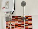 Compact instant water heater and showerhead in a bathroom with red mosaic tiles