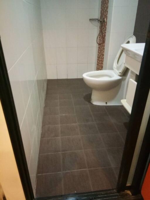 Compact bathroom with wall-mounted toilet and walk-in shower area