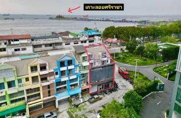 Aerial view of a coastal residential area with buildings, road, and distant water view