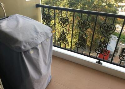 Covered item on a residential balcony with decorative railing and a view of trees