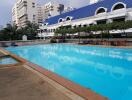 Large communal swimming pool with surrounding seating area in a residential complex