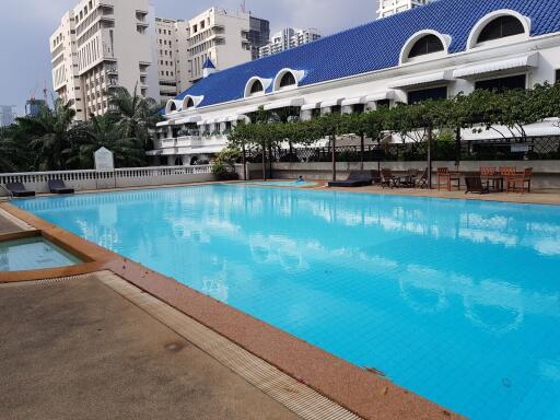 Large communal swimming pool with surrounding seating area in a residential complex