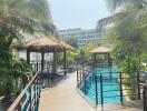 Inviting pool area with tropical huts and surrounding apartment complex