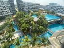 Lush tropical amenity area with swimming pools and palm trees in residential complex